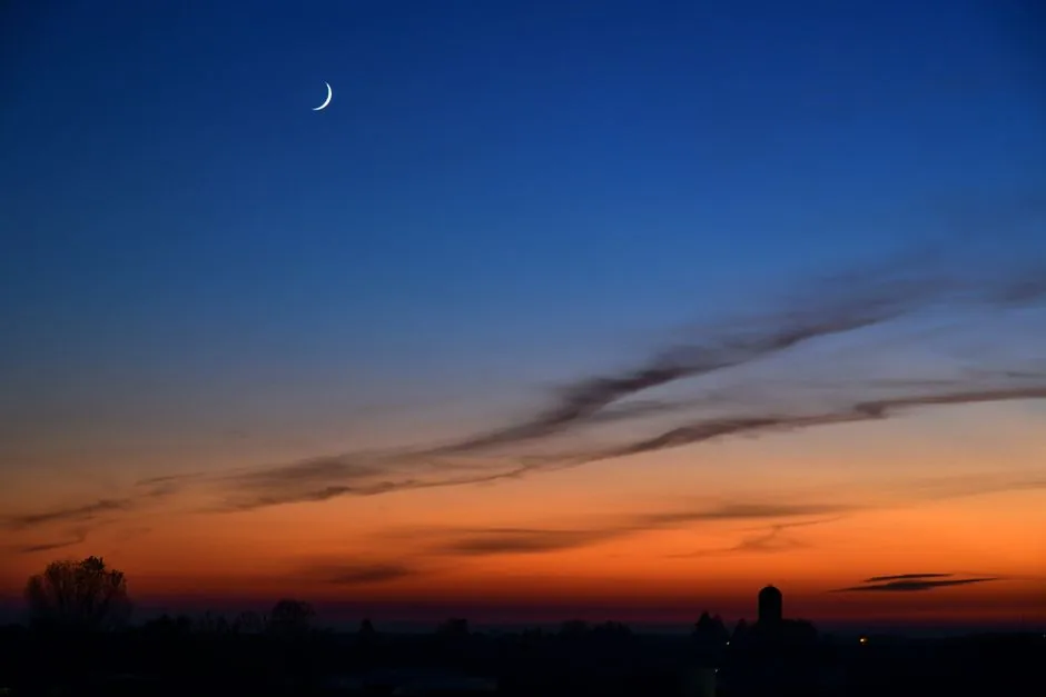 A serene twilight sky with a crescent moon over Rizza, Veneto, Italy.