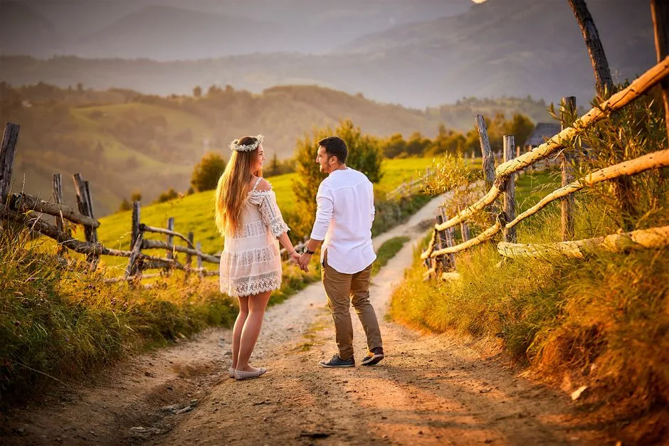 A couple holding hands on a rustic road in Romania, capturing a romantic moment in nature.